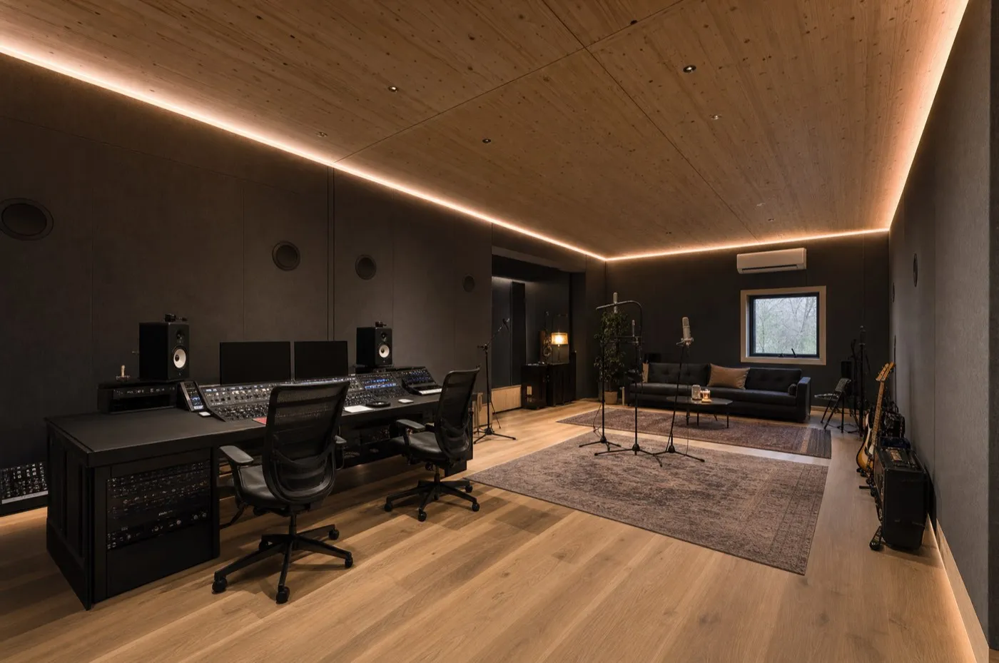 TWO Studio interior: dark fabric-wrapped walls, a mixing console with monitors, a couch and a recording corner under a wooden ceiling